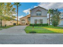 Charming two-story home with manicured lawn, lush landscaping, and concrete driveway in a sunny neighborhood at 149 Emeraldview Ave, Davenport, FL 33897