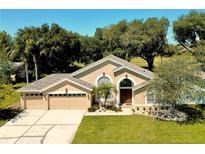 Charming home featuring a well-manicured lawn, three-car garage, and an elegant entryway with arched windows at 1969 Crystal Downs Ct, Oviedo, FL 32765