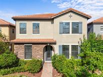 Charming two-story home featuring a stone facade, terracotta roof, and lush landscaping at 1978 Fishtail Fern Way, Ocoee, FL 34761