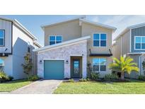 Inviting home featuring a stone accent wall, a well-manicured lawn, and a charming, colored garage door at 2821 Bookmark Dr, Kissimmee, FL 34746