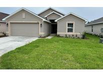 Beige single-Gathering home featuring an attached two-car garage, well-manicured lawn, and neutral-tone exterior paint at 4586 Se 25Th Loop, Ocala, FL 34480