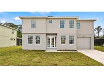Two-story home boasts a symmetrical design with a well-manicured lawn and attached one-car garage at 4905 Pall Mall E St, Kissimmee, FL 34758