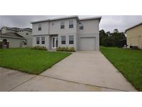 Inviting two-story home featuring a well-maintained lawn, attached garage, and neutral gray color scheme at 4905 Pall Mall E St, Kissimmee, FL 34758