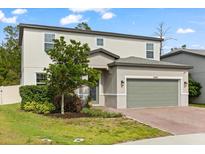 Two-story home with a two car garage, brick driveway, neutral paint scheme and manicured landscaping at 5458 Carrara Ct, St Cloud, FL 34771