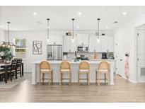 Bright, open kitchen with white cabinetry, stainless steel appliances, and a large center island with seating at 5458 Carrara Ct, St Cloud, FL 34771