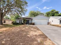 Charming single-story home features a two-car garage and well-maintained front yard with mature trees at 6042 Brookhill Cir, Orlando, FL 32810