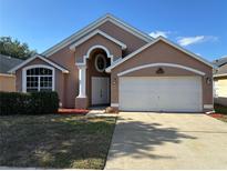 Charming single-Gathering home with a two-car garage and manicured landscaping under a bright blue sky at 6625 Cherry Grove Cir, Orlando, FL 32809