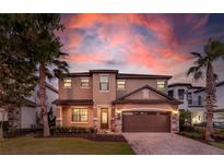 Charming two-story home with well-manicured lawn, stone accents and two-car garage, set against a colorful sunset sky at 8180 Valhalla Ter, Reunion, FL 34747
