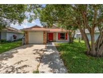 Charming single-story home featuring brick accents, a red front door, and mature trees in a well-maintained yard at 916 Glendale St, Orlando, FL 32807