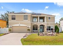 Inviting two-story home featuring a well-manicured lawn, garden, and solar panels, creating an appealing curb presence at 16 Sawfish Ct, Kissimmee, FL 34759