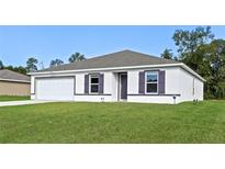 Charming single-story home with a well-manicured lawn, attached garage, and simple, modern design at 2701 Sw 153Rd Ln, Ocala, FL 34473