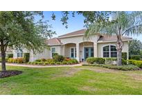Charming, landscaped front yard featuring a lush lawn, colorful plants, and mature trees accentuating this inviting home at 31754 Red Tail Blvd, Sorrento, FL 32776