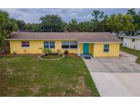 Charming yellow home with a well-manicured lawn, bright blue door, and a quaint circular flower bed at 3300 Needles Dr, Orlando, FL 32810