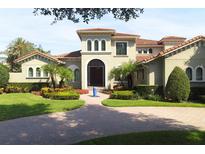 Elegant Mediterranean-style home featuring a tile roof, lush landscaping, and a circular driveway with a front water feature at 11013 Ullswater Ln, Windermere, FL 34786