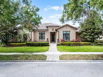 Charming single-story home with lush landscaping and a brick walkway leading to the front door at 11755 Waterstone Loop Dr, Windermere, FL 34786