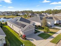 Aerial view of home with solar panels, manicured lawn and landscaping, and a two car garage at 2941 Marlberry Ln, Clermont, FL 34714