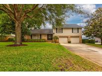Charming two-story home featuring a well-manicured lawn, mature trees, and a two-car garage at 3241 Downs Cove Rd, Windermere, FL 34786