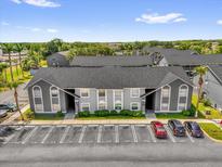 Condominium building featuring a well-kept gray exterior and ample parking with mature landscaping at 4160 Pershing Pointe Pl # 4, Orlando, FL 32822