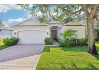Charming single-story home featuring a well-manicured lawn, brick driveway, and lush landscaping at 4301 Heirloom Rose Pl, Oviedo, FL 32766