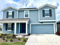 Charming two-story home with blue siding, black shutters, and a well-manicured front yard at 4427 Blackbird St, Kissimmee, FL 34746