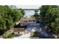 Aerial view of a beige two-story home with a three-car garage and a nearby private dock on the lake at 4981 Lake Cecile Dr, Kissimmee, FL 34746