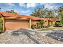 Inviting exterior view of home with a red tile roof, spacious driveway, and attached garage at 5039 Jamaica # 10, Orlando, FL 32808