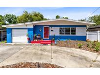 Charming single-story home with a bright blue and white exterior, red door, and well-maintained landscaping at 657 Overspin Dr, Winter Park, FL 32789
