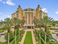 Resort exterior shows manicured walkway leading to the building entrance with palm trees, gardens, and porte cochere at 7593 Gathering Dr # 502, Reunion, FL 34747