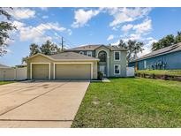 Inviting two story home featuring an attached three car garage and a well manicured lawn at 9532 Water Fern Cir, Clermont, FL 34711