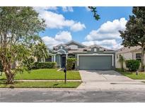 Charming single-story home featuring a well-manicured lawn, mature landscaping, and an attached two-car garage at 9563 Myrtle Creek Ln, Orlando, FL 32832