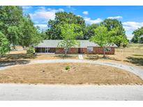 Charming single-story brick home with mature trees and circular driveway on a sunny day at 106 8Th St, Lake Hamilton, FL 33851