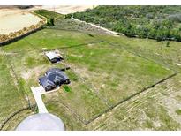 Expansive fenced property features a house, outbuilding, pool, and circular driveway surrounded by lush green pastures at 11115 Romance Ct, Winter Garden, FL 34787