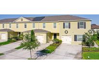 Two-story townhome showcasing a well-maintained lawn, solar panels, and a one car garage at 12340 Bowes Branch Rd, Orlando, FL 32824