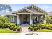 Charming home featuring manicured landscaping, covered porch, and a red front door at 13701 Chauvin Ave, Orlando, FL 32827