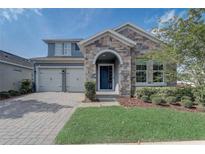 Charming home featuring stone accents, a welcoming front door, well-manicured landscaping, and a two car garage at 15378 Gilligan Ct, Winter Garden, FL 34787