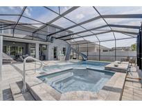 Beautiful screened-in pool area with a built-in spa, water slide, and a covered lanai with ample seating at 15378 Gilligan Ct, Winter Garden, FL 34787
