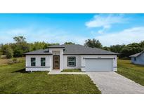 Charming single-story home with a white exterior, gray roof, paver driveway, and well-manicured lawn at 16655 Sw 43Dr Terrrace Rd, Ocala, FL 34473