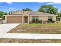 Charming single-story home with a two-car garage and well-maintained lawn and blue skies at 2104 E Parkton Dr, Deltona, FL 32725