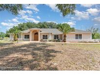 Inviting single-story home featuring a symmetrical facade, arched entryway, and well-maintained landscaping at 22619 State Road 44, Eustis, FL 32736
