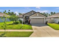 Charming single-story home featuring a well-manicured lawn and a two-car garage at 228 Bergamot Loop, Davenport, FL 33837