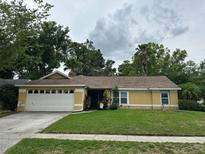 Charming yellow single-Gathering home with a well-maintained lawn and a two car garage at 243 Country Landing Blvd, Apopka, FL 32703