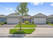 Charming home featuring a well-manicured lawn, paver driveway, two-car garage and a cozy front porch at 2960 Cherry Blossom Loop, St Cloud, FL 34771