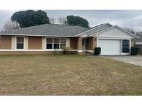 Cozy one-story home featuring a gray roof, brown siding, an attached garage, and a well-maintained front lawn at 42 Banyan Pass, Ocala, FL 34472