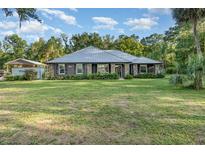 Inviting single-story home featuring a well-manicured lawn, stone accents, and a durable metal roof at 433 Tangerine Ave, Lake Helen, FL 32744