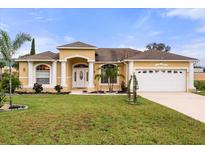 Inviting single-story home with a well-manicured lawn, columns, and a two-car garage at 507 Westwind Dr, Davenport, FL 33896