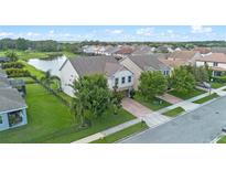 A beautiful aerial view of a two-story home with a lush green lawn and brick driveway near a pond at 646 Marsh Reed Dr, Winter Garden, FL 34787