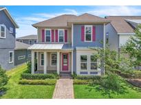 Charming two-story home featuring pink shutters, a covered front porch, and manicured landscaping at 8226 Nemours Pkwy, Orlando, FL 32827
