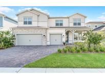 Charming two-story home featuring a three-car garage, brick driveway, and a well-manicured lawn at 13758 Tybee Beach Ln, Orlando, FL 32827