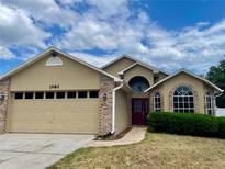 Charming one-story home featuring a two-car garage, brick accents, and a well-manicured lawn at 1980 Aquarius Ct, Oviedo, FL 32766