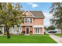Charming two-story townhome featuring a landscaped front yard with healthy green grass and a welcoming entrance and walkway at 2204 San Vittorino Cir # 102, Kissimmee, FL 34741